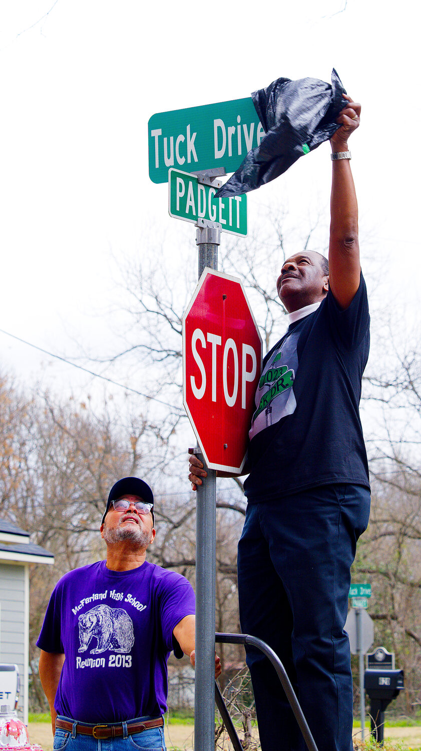 Longtime city councilman Mitch Tuck does the honors of unveiling the sign as Carlist Brinkley steadies the ladder.